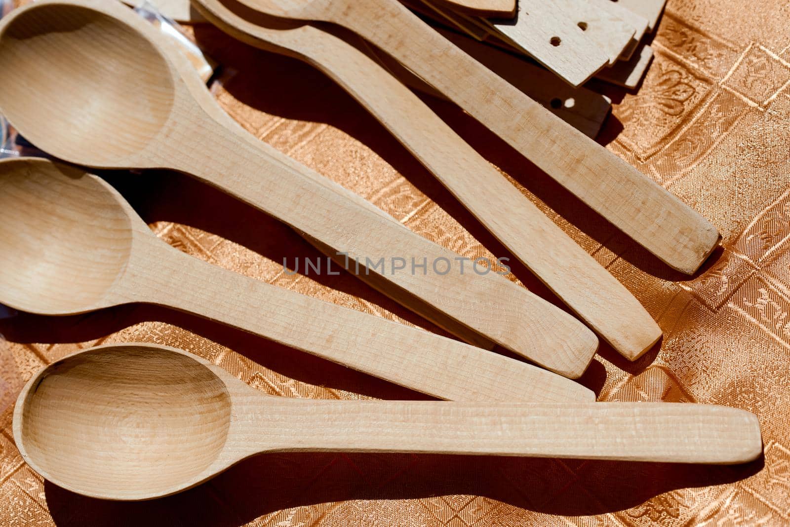 handmade wood spoons on wooden table under sun by AntonIlchanka