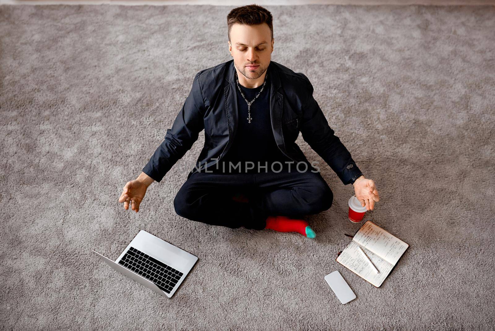 Reflective man with laptop sit in lotus on carper  by AntonIlchanka