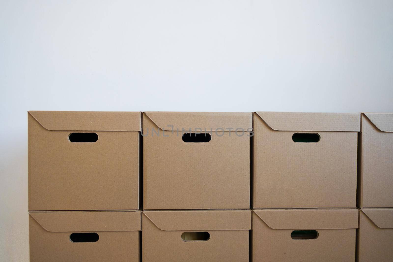 Cardboard boxes for storage that are neatly stacked against a white wall. Concept of delivery.