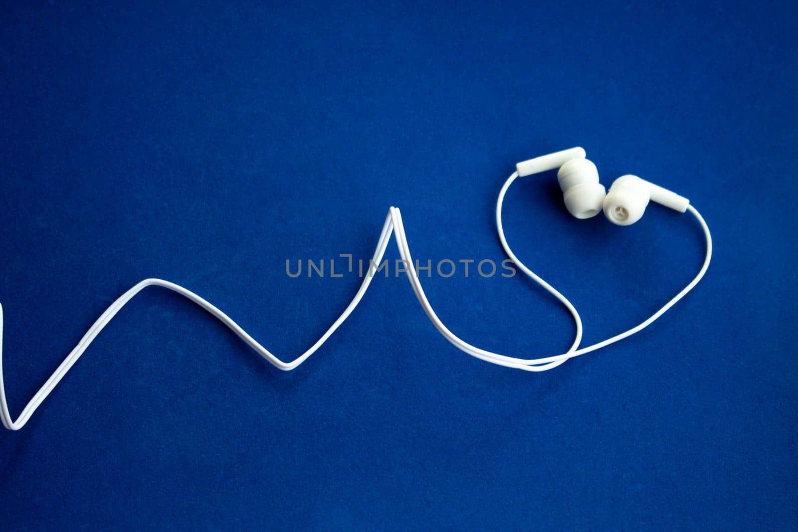 White headphones on blue background with copy space.