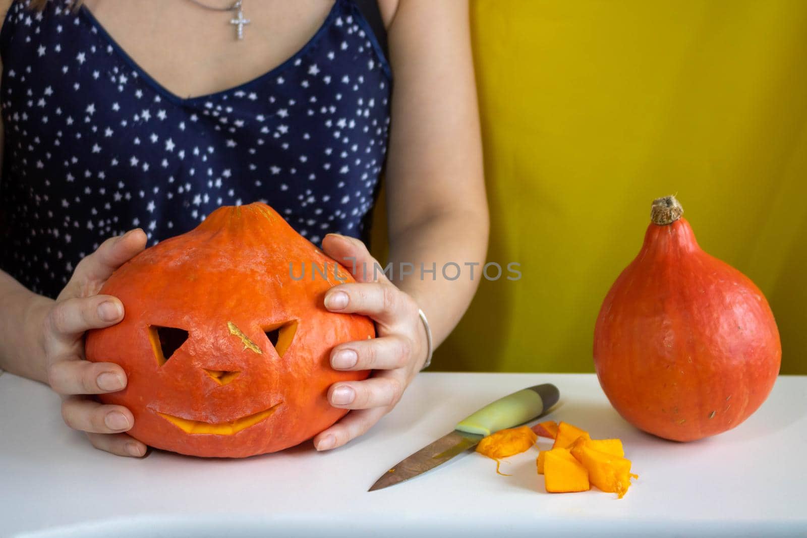 The concept of Halloween, decorations and holidays. Women's hands hold a pumpkin.