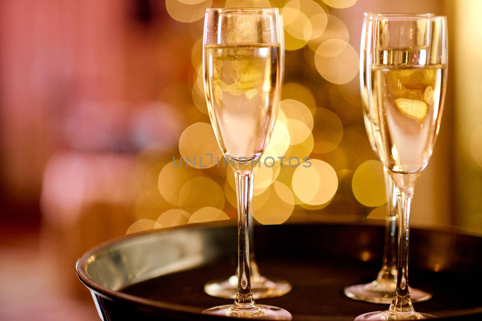 Full glasses of champagne on black tray with colorful bokeh. High quality photo