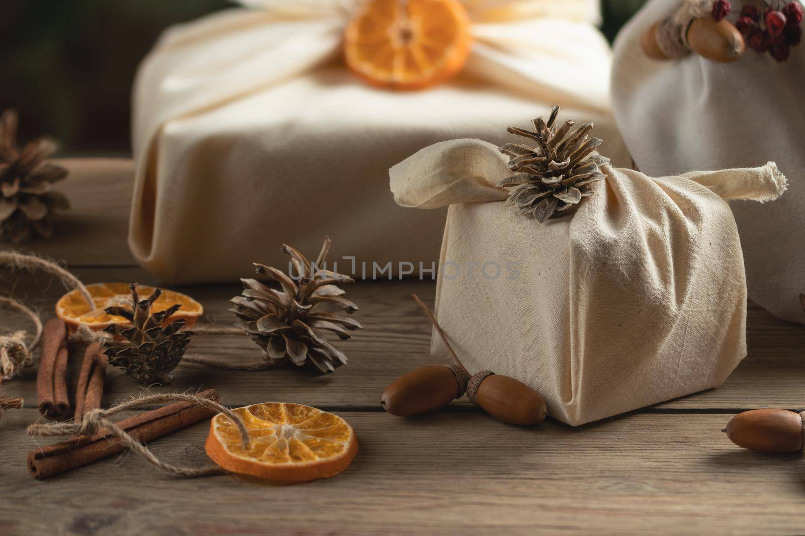 Zero waste christmas concept. Packed in natural fabric gifts and decorations from natural materials on a wooden table.