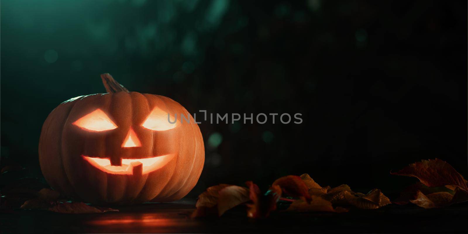 Halloween pumpkin head jack lantern with glowing eyes on wooden table by galsand