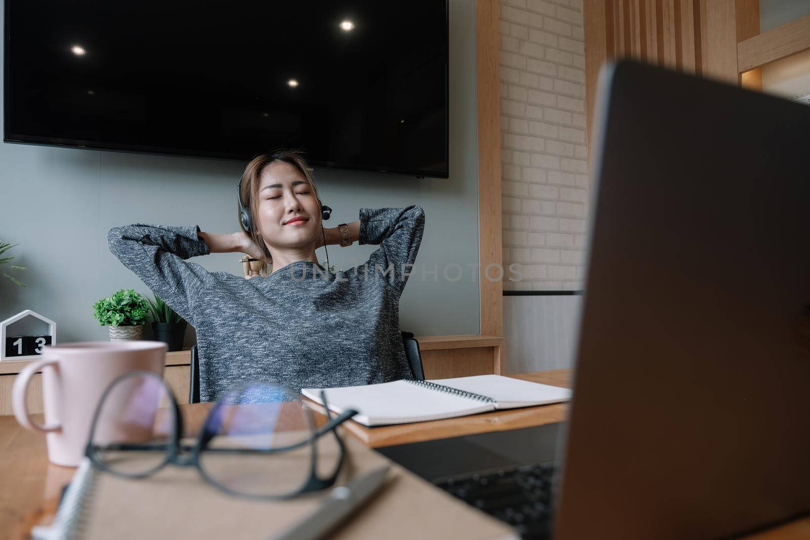 Happy prepared girl student taking break from study at home with books and laptop relaxing holding hands behind head, smiling satisfied woman finished work sitting at desk enjoy no stress relief.