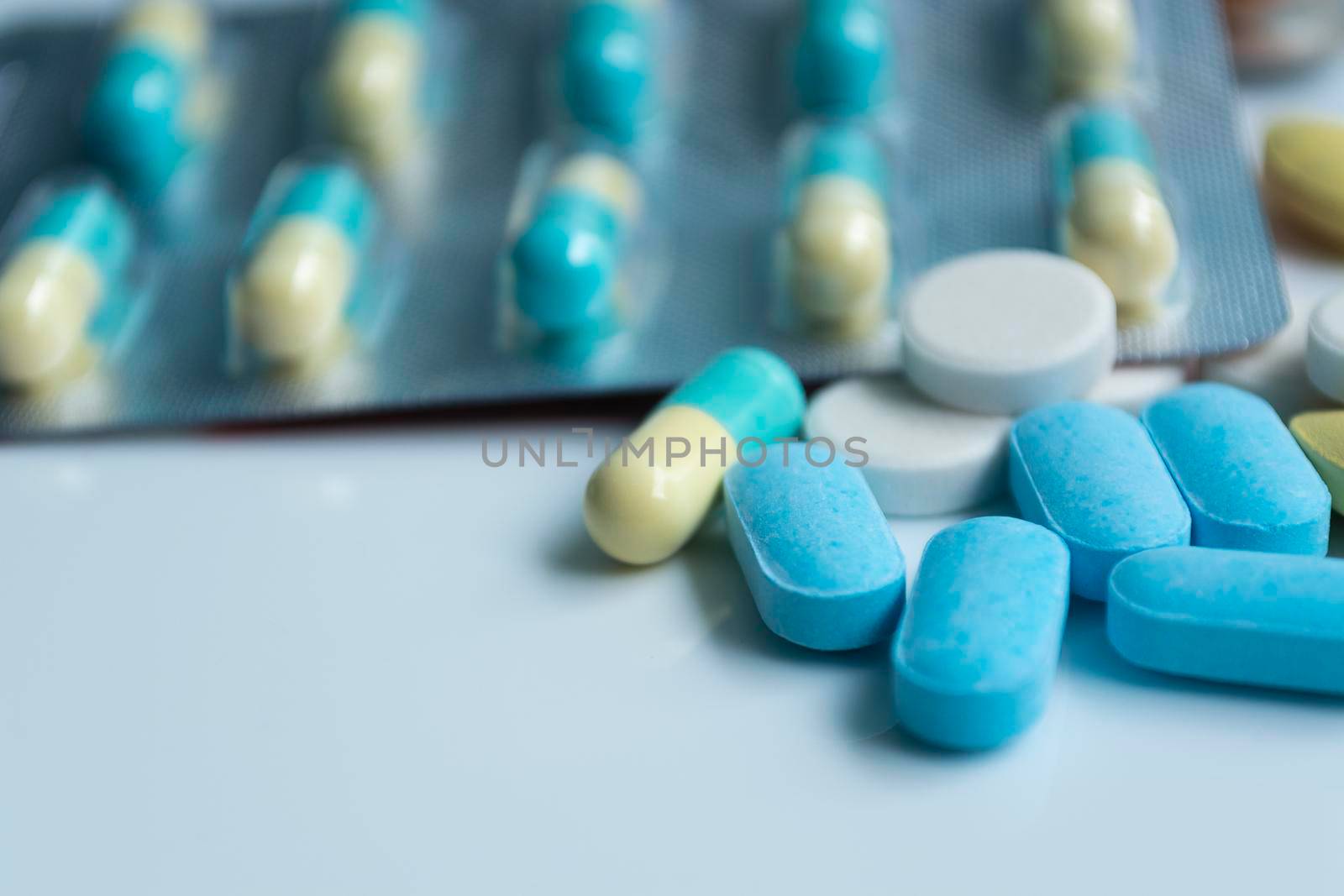 Assorted pharmaceutical medicine pills, tablets and capsules with blurred background over white background. Concept of healthcare and medicine