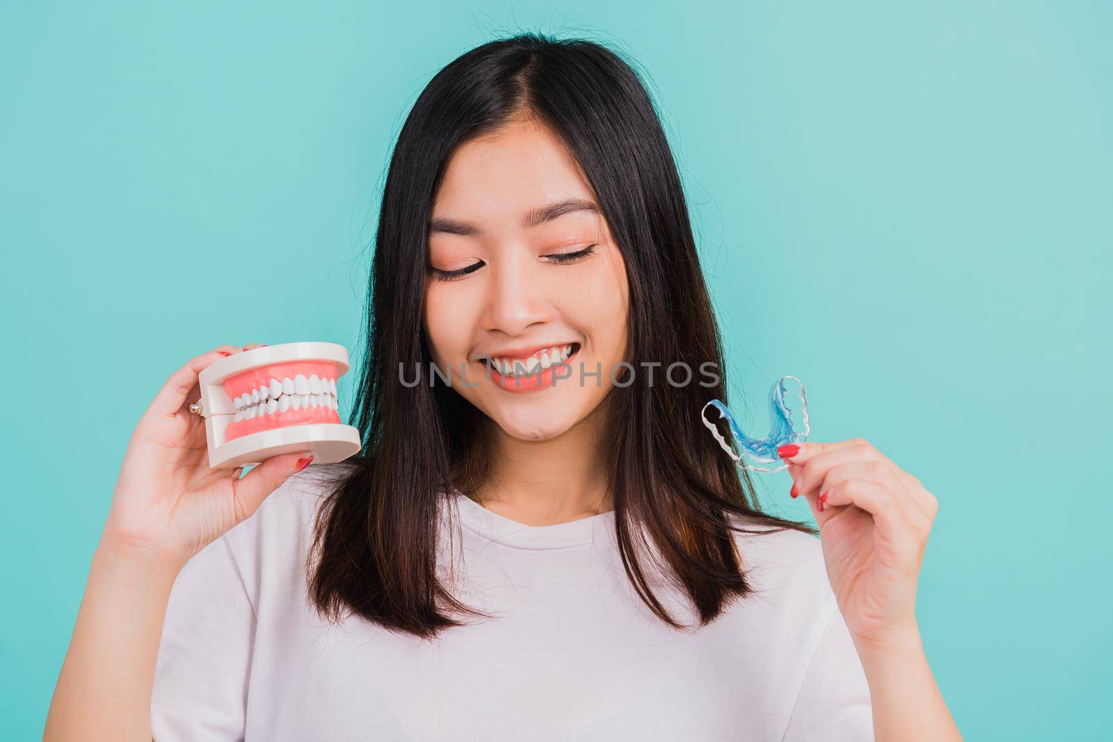 woman smiling holding silicone orthodontic retainers for teeth retaining by Sorapop