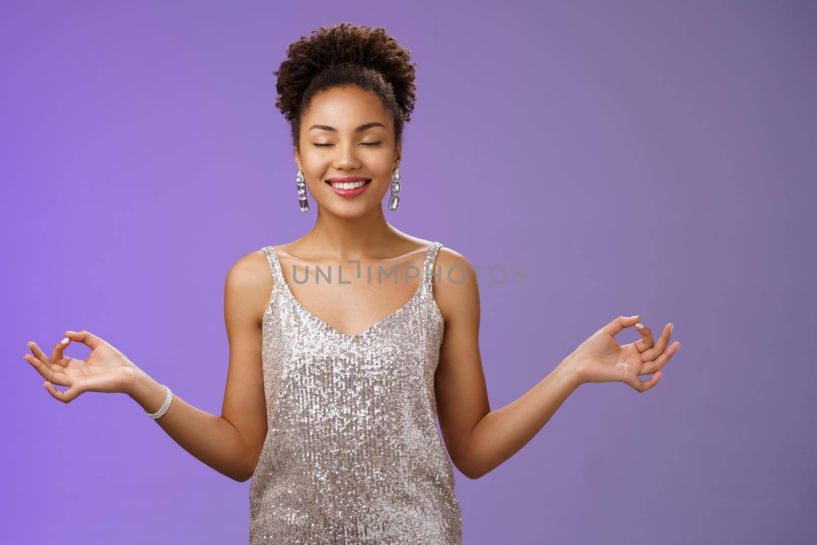 Happy relieved elegant african american woman luxurious evening silver glittering dress smiling happily feel rejoice stress-free calm down meditating breathing excercise find nirvana yoga pose by Benzoix