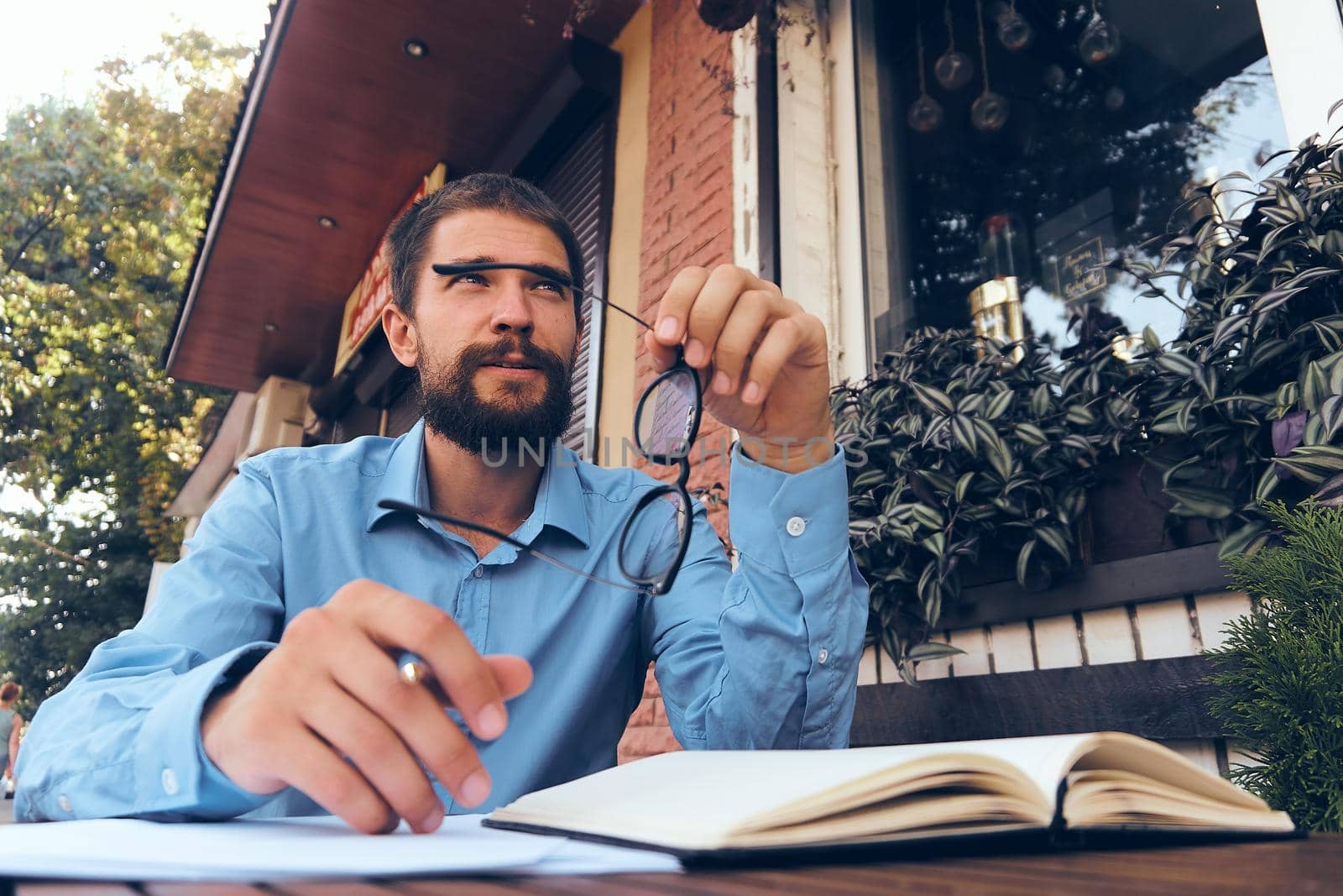 bearded man in blue shirt works with papers in a cafe by Vichizh