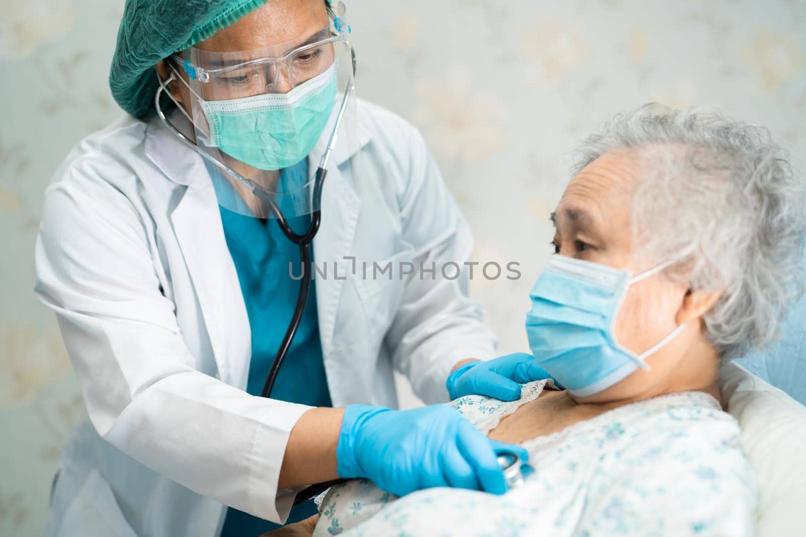 Asian doctor wearing face shield and PPE suit new normal to check patient protect safety infection Covid-19 Coronavirus outbreak at quarantine nursing hospital ward.