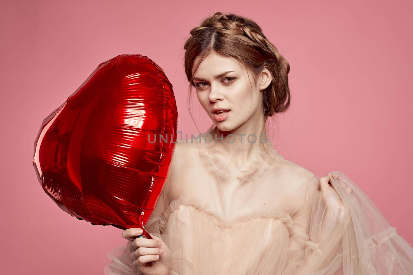 beautiful woman red heart in the hands of the balloon pink background. High quality photo