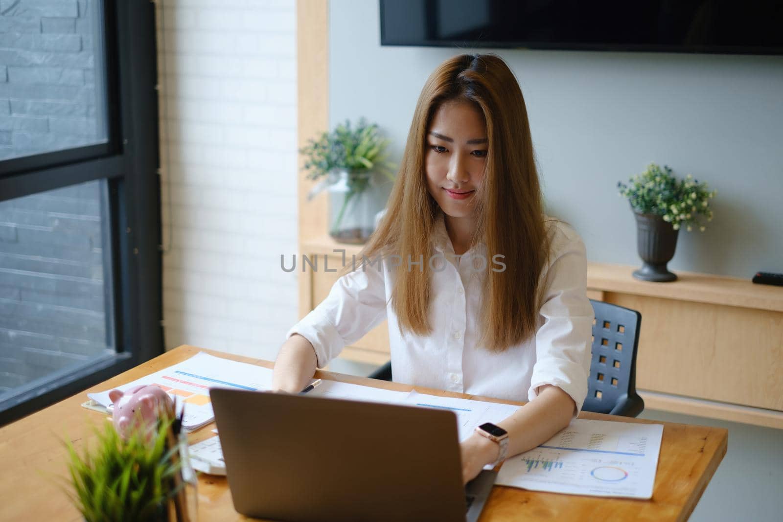 Photo of gorgeous secretary working at office. she sitting at the wooden desk. by itchaznong