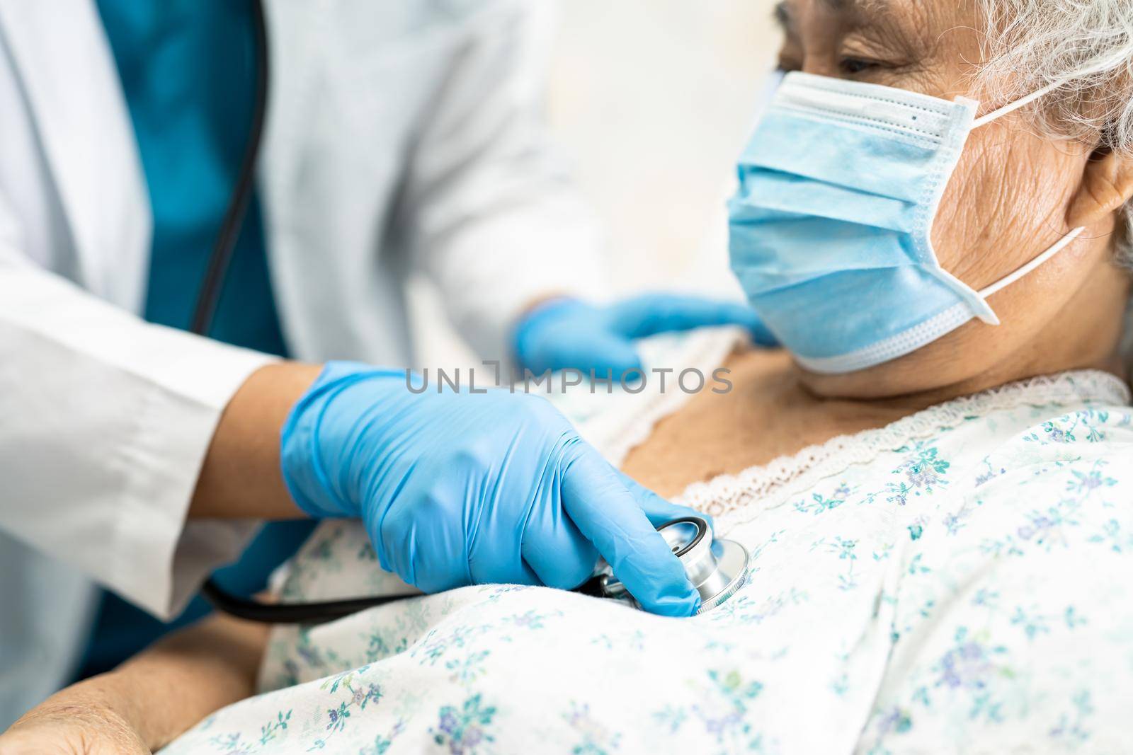 Doctor using stethoscope to checking Asian senior or elderly old lady woman patient wearing a face mask in hospital for protect infection and kill Novel Coronavirus Covid-19 virus.