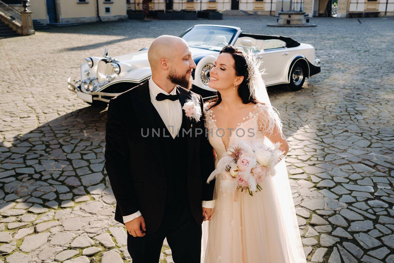 Elegant wedding couple In the courtyard of the castle near a retro car by Lobachad