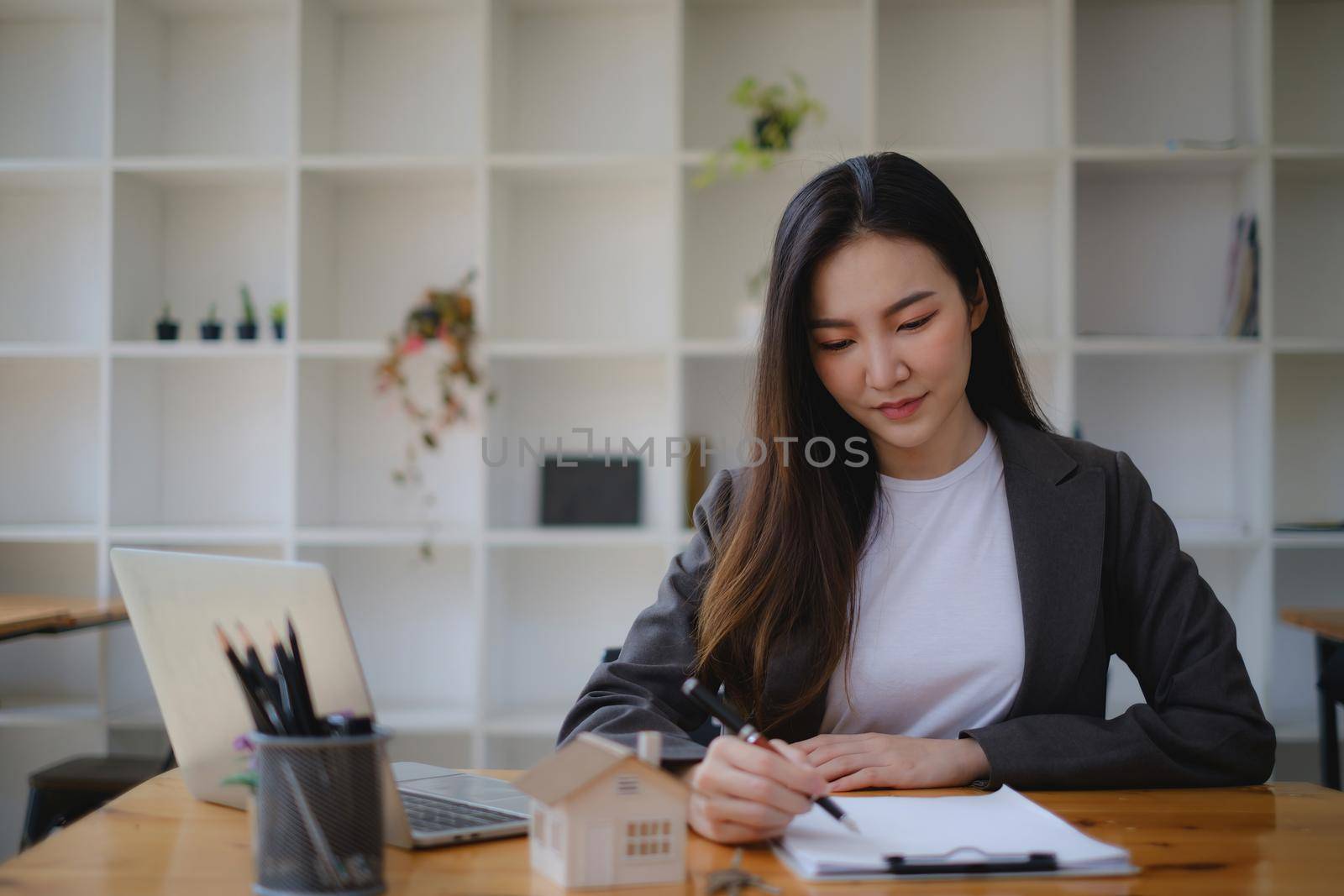 Close up of Business woman checking document before signing agreement for buying house. Bank manager and real estate concept. by itchaznong