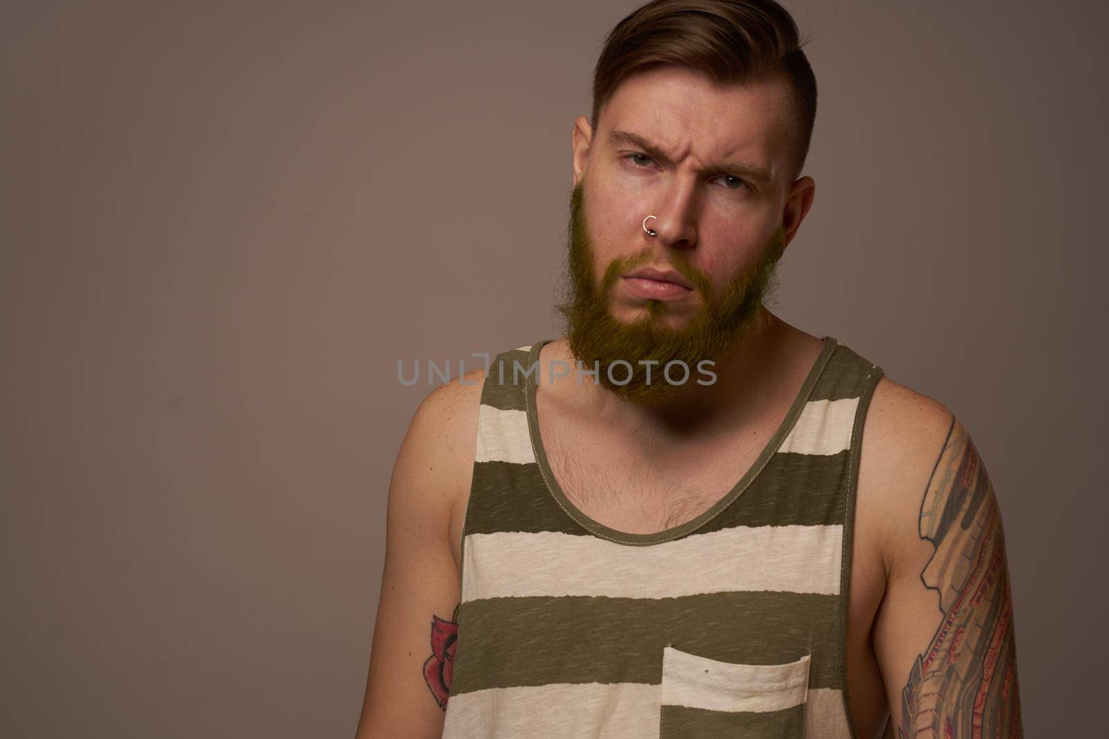 fashionable man with tattoos on his arms stylish hairstyle self-confidence studio by Vichizh