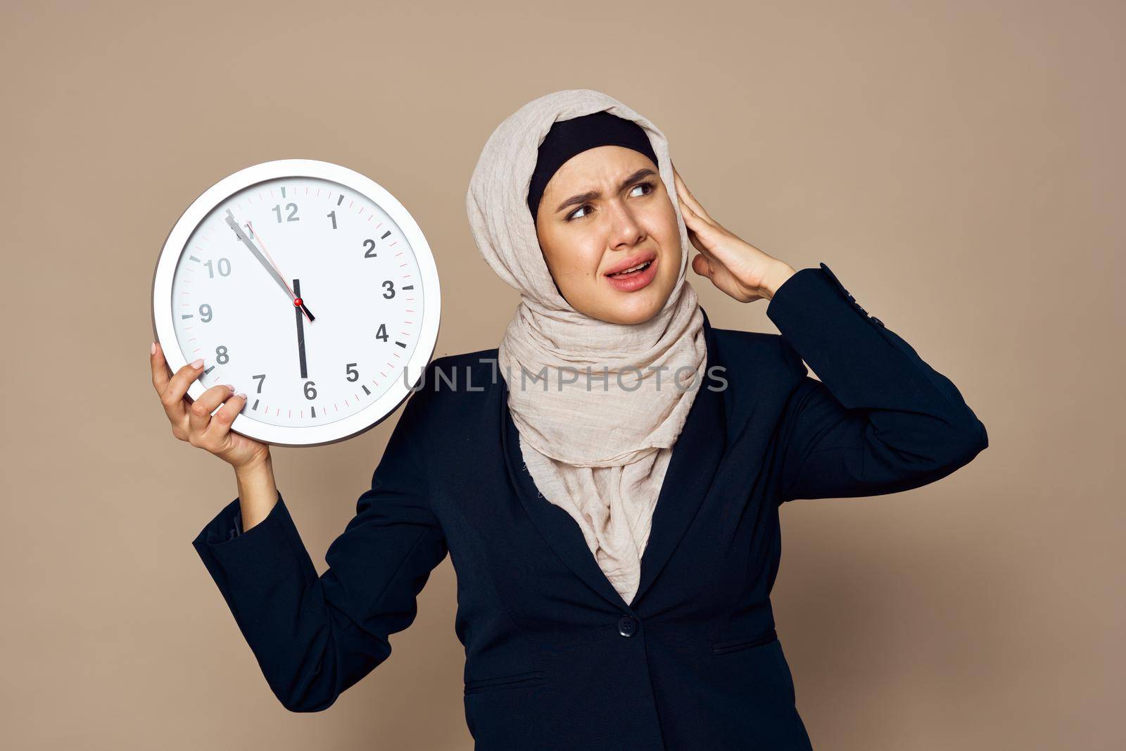 woman in hijab with clock in hands work office beige background by Vichizh