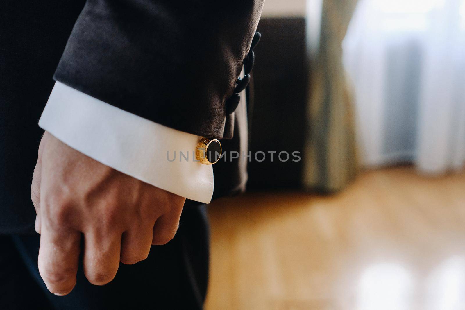 Close-up of a man's hands in a black formal suit with cuffs.