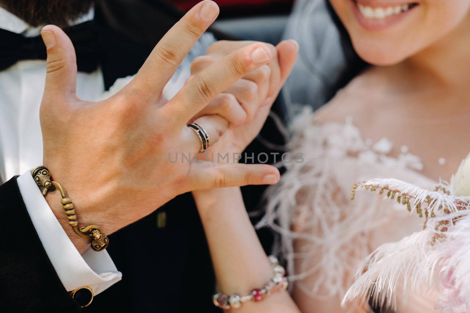 Close-up of the palms of the bride and groom with wedding rings on their hands.