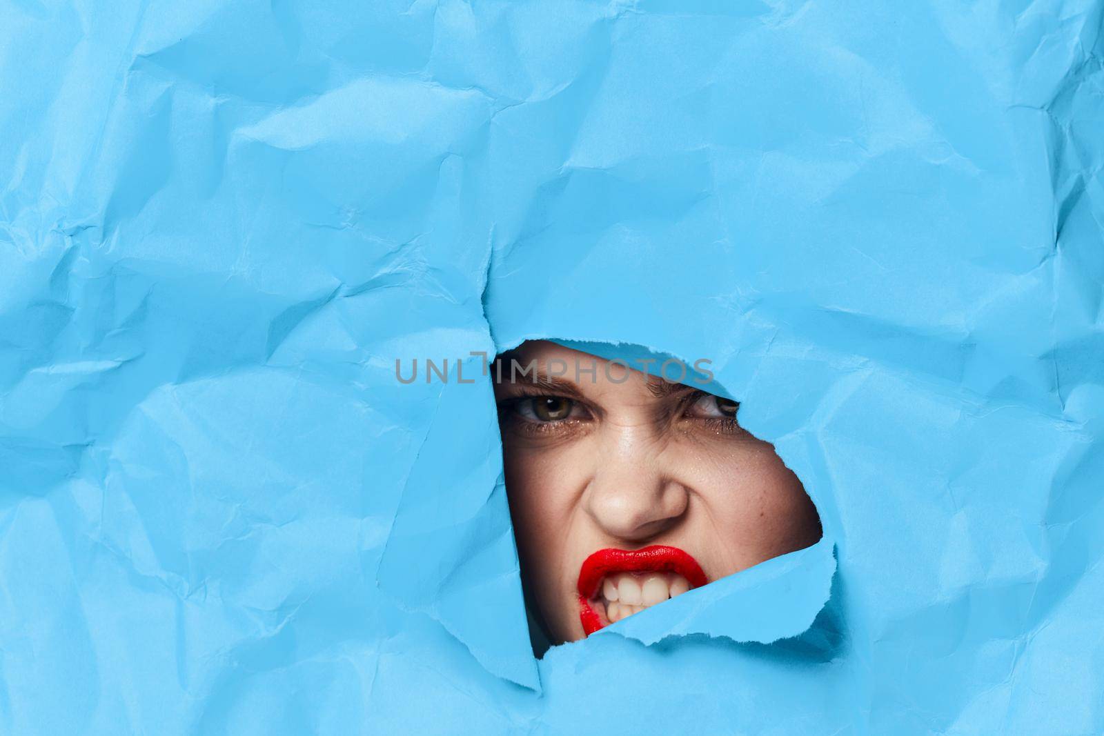 woman's face breaks through blue mockup close-up. High quality photo