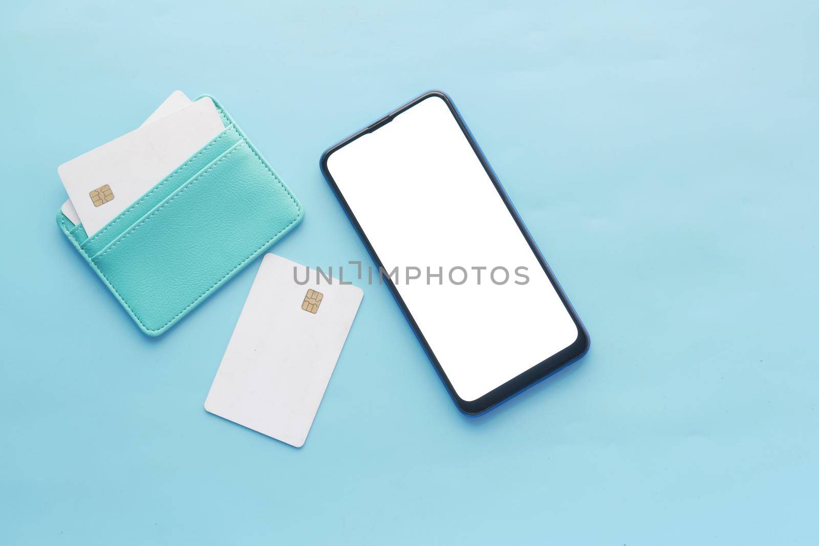 smart phone with empty screen , credit card on blue background .