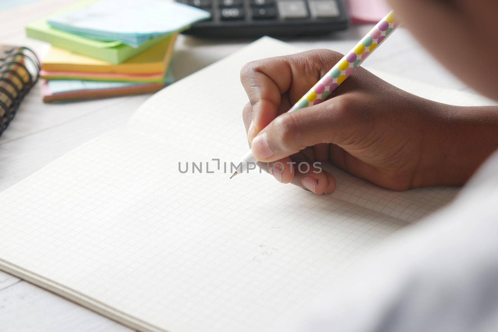 6 year old child girl hand writing on notepad sitting on a chair