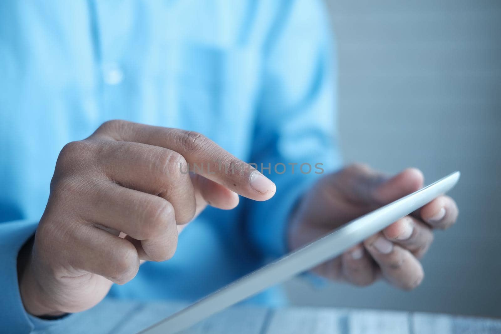 man's hand working on digital tablet at office desk