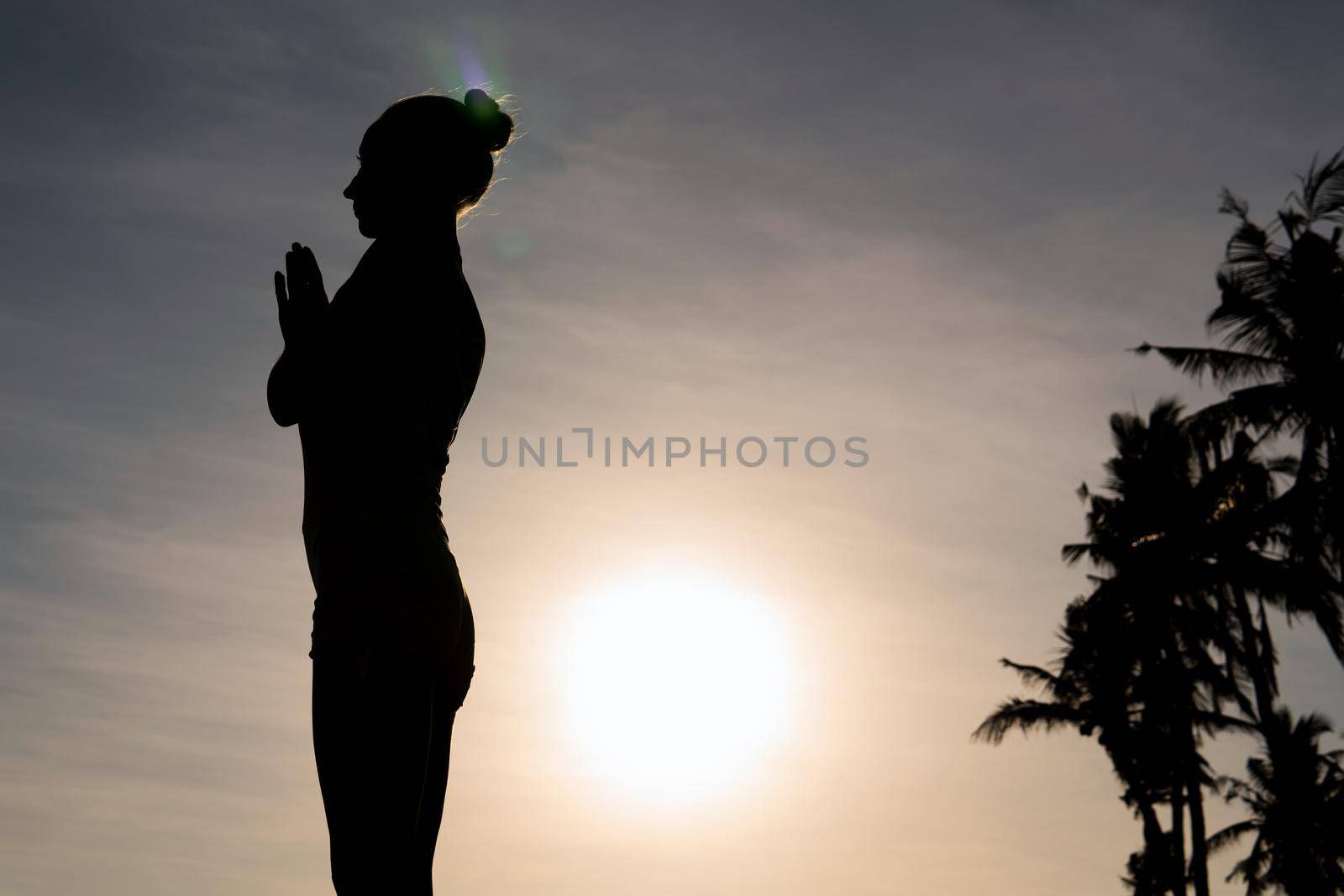 beautiful woman meditating outdoors. bali beach with palms