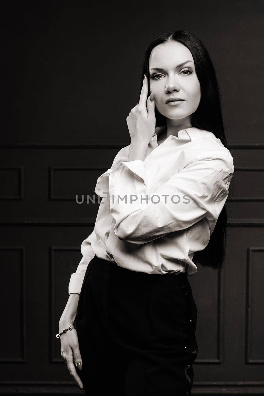 Elegant brunette in a white shirt on a dark background.black and white photo.