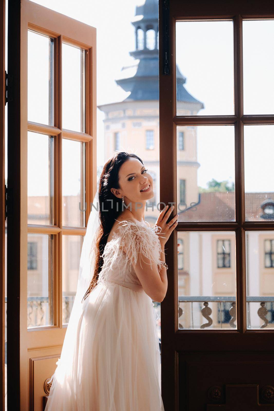 An elegant bride on the balcony of an ancient castle in the city of Nesvizh.
