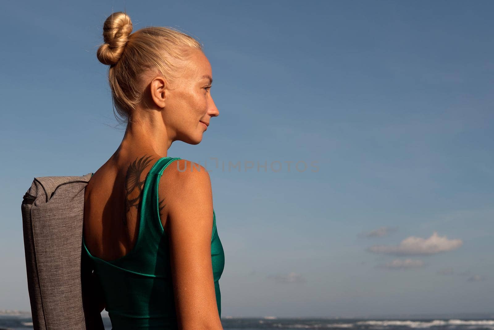 beautiful girl walking on the beach with yoga mat. bali