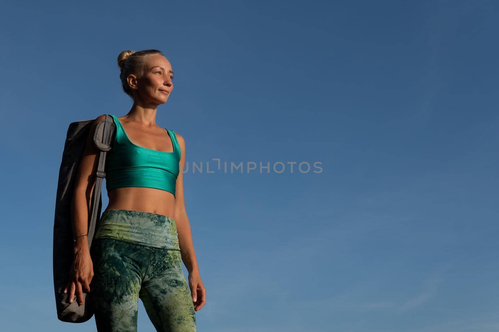 beautiful girl walking on the beach with yoga mat. by Alexzhilkin