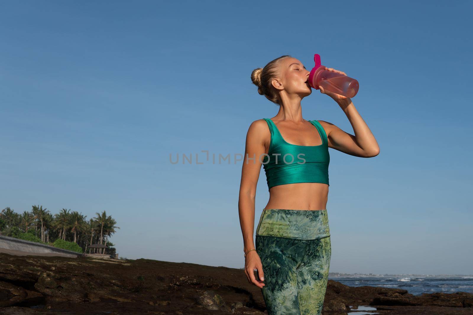 beautiful woman drinking water on the beach. bali