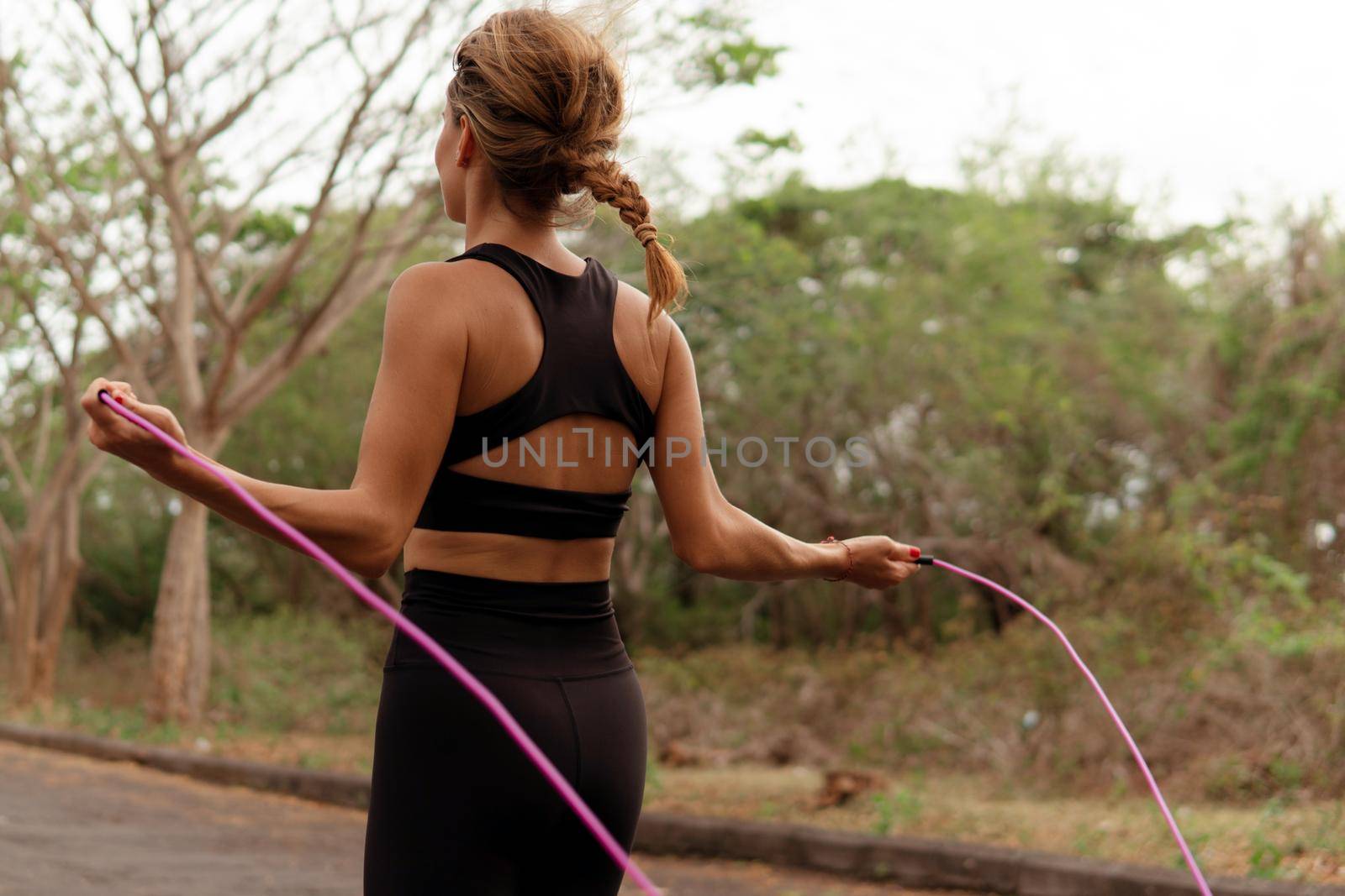 Woman in black sportwear jumping rope by Alexzhilkin