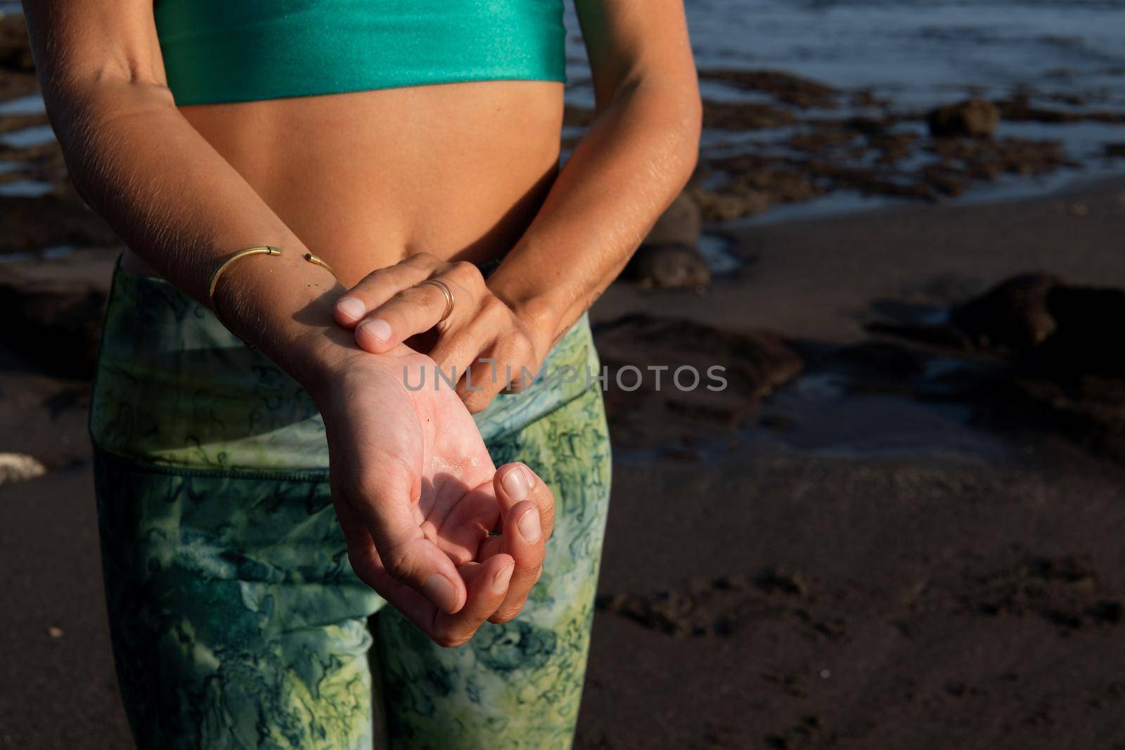 woman in green sportwear measures her pulse. bali