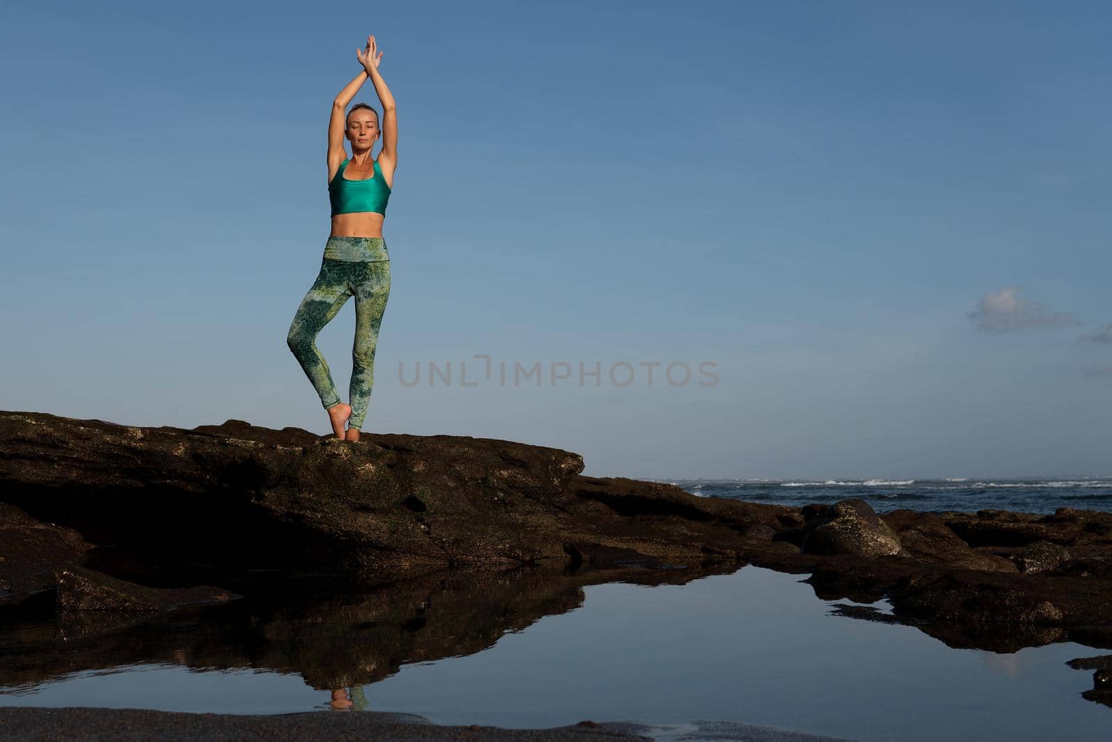 beautiful woman doing yoga on the beach by Alexzhilkin