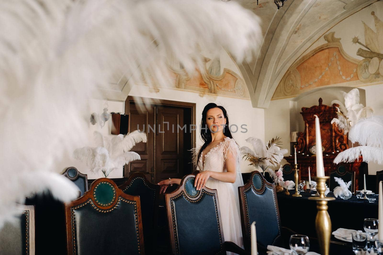 A stylish bride in a wedding dress in the interior of a restaurant decorated with feathers on the tables.