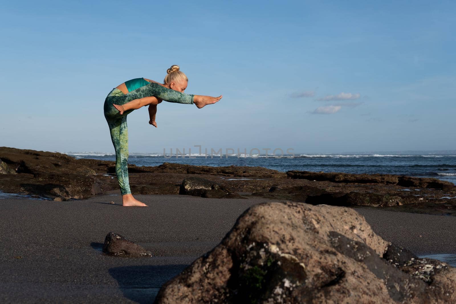 beautiful woman doing yoga on the beach by Alexzhilkin