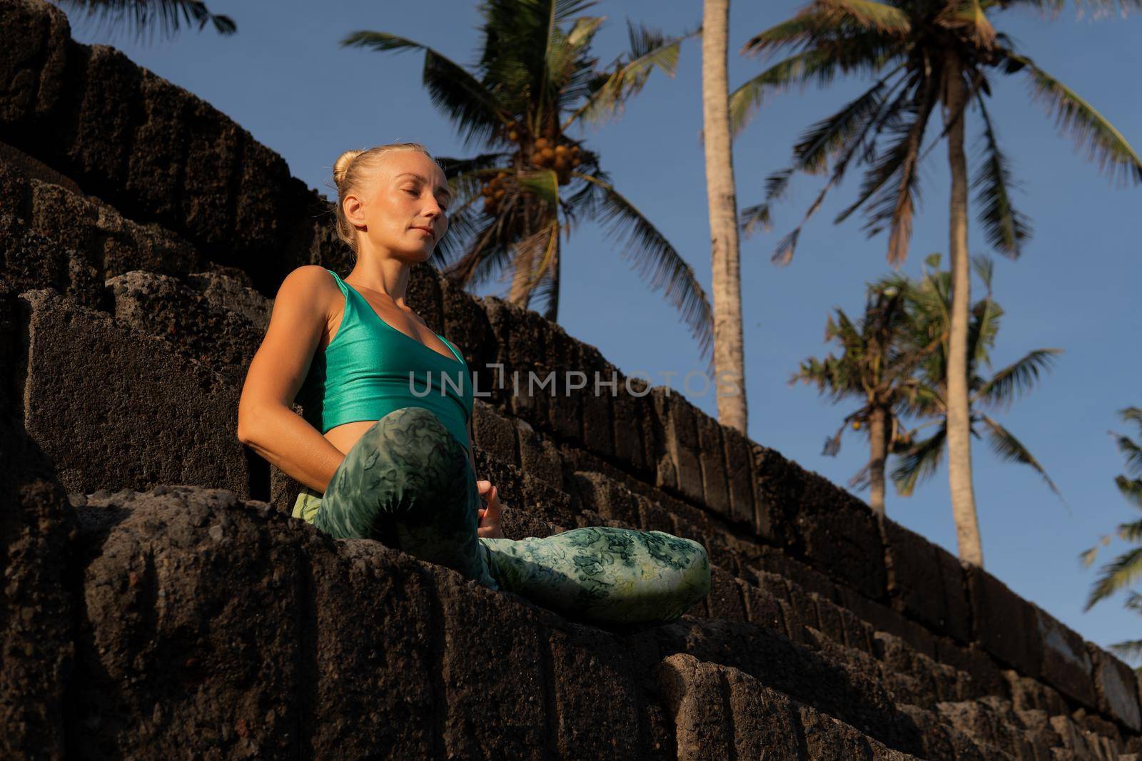 beautiful woman meditating outdoors. bali beach with palms