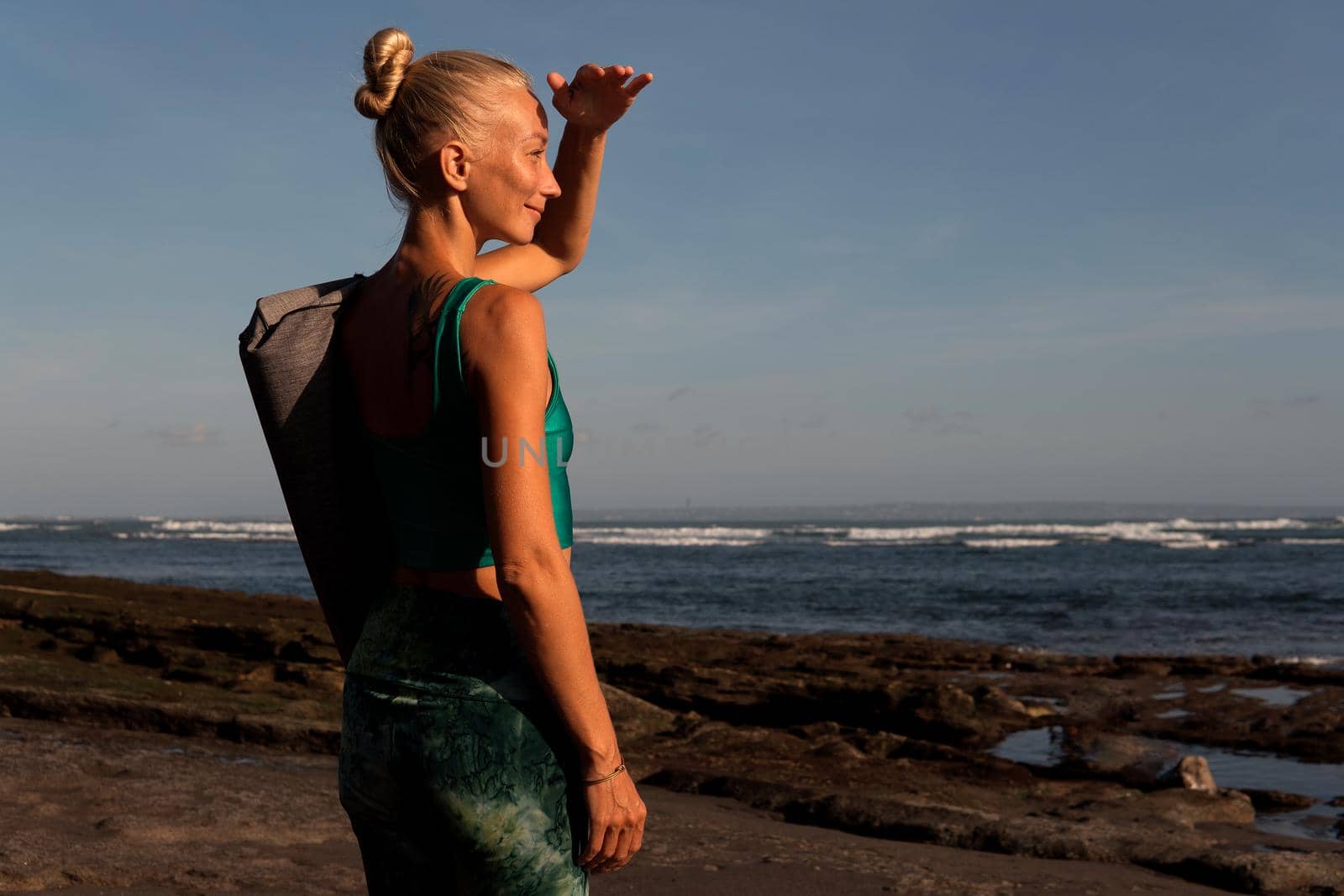 beautiful girl walking on the beach with yoga mat by Alexzhilkin