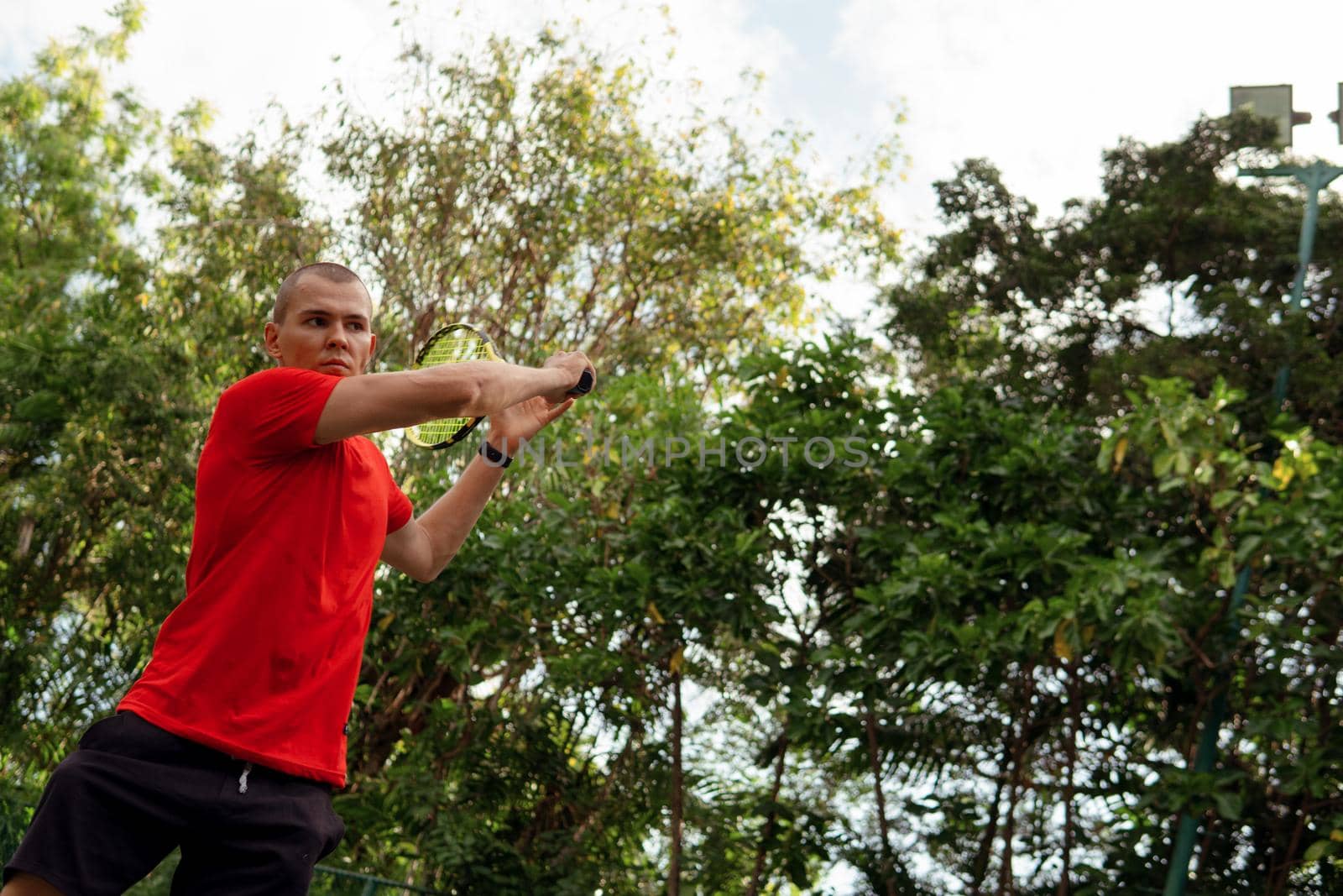 man in red sportwear playing tennis by Alexzhilkin