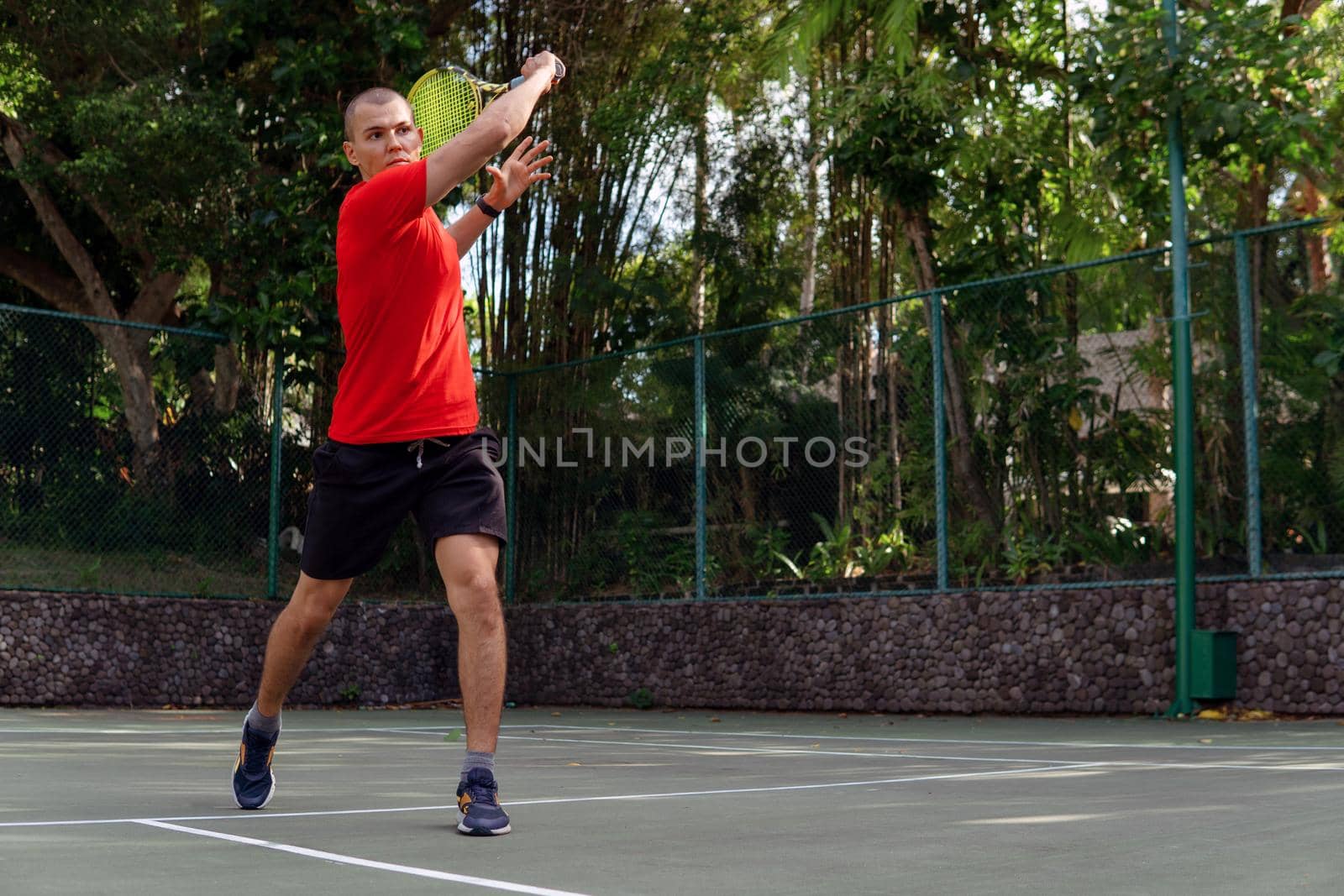 man in red sportwear playing tennis. bali
