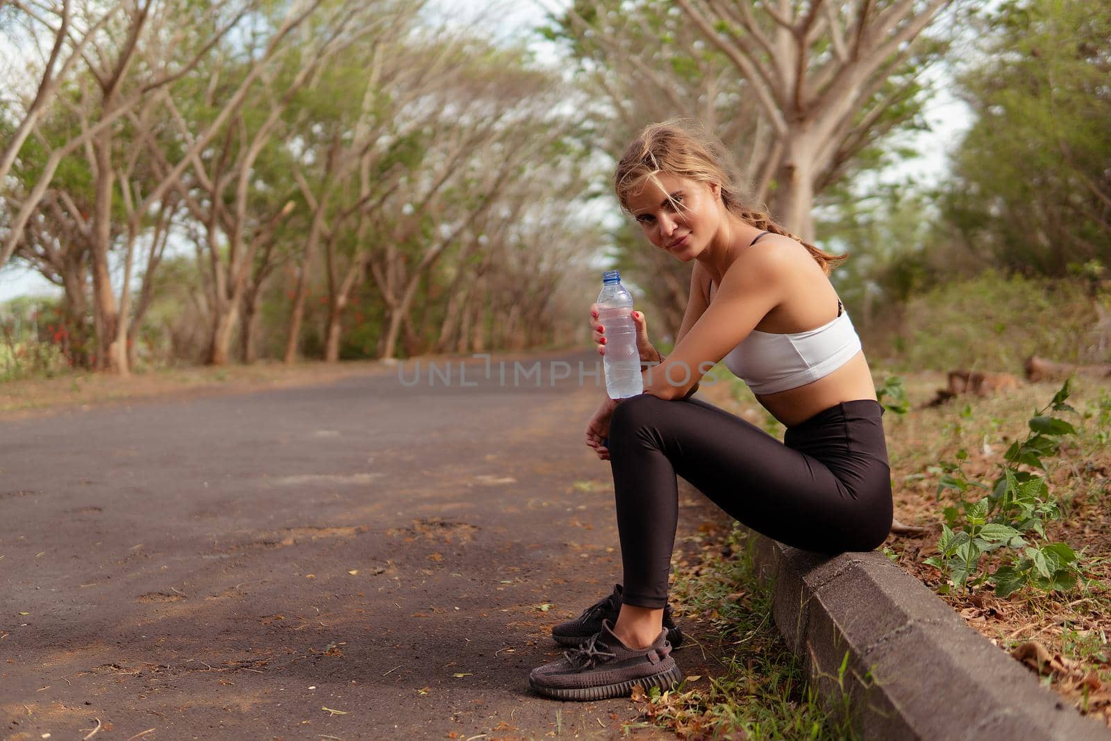 Woman in sport wear drinking water in the park. bali