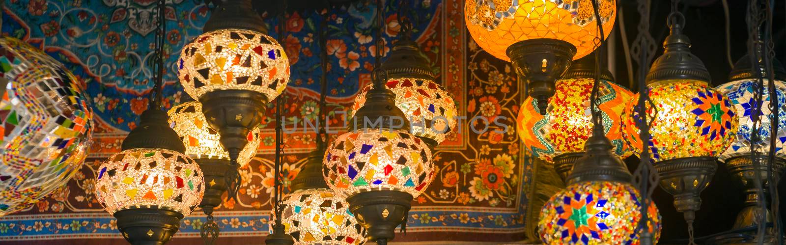 Middle Eastern lambas of different colors and sizes are hanging in the bazaar. Bright traditional Arabic and Turkish lanterns made of metal and glass, inlaid with mosaic details of different colors.