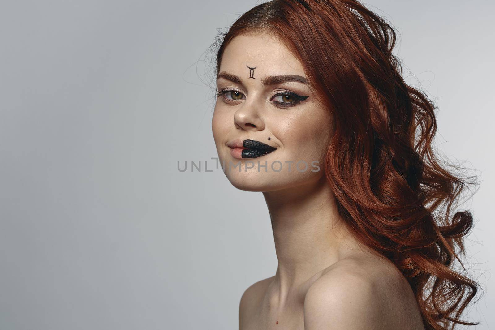 red-haired woman naked shoulders zodiac sign on face gemini. High quality photo