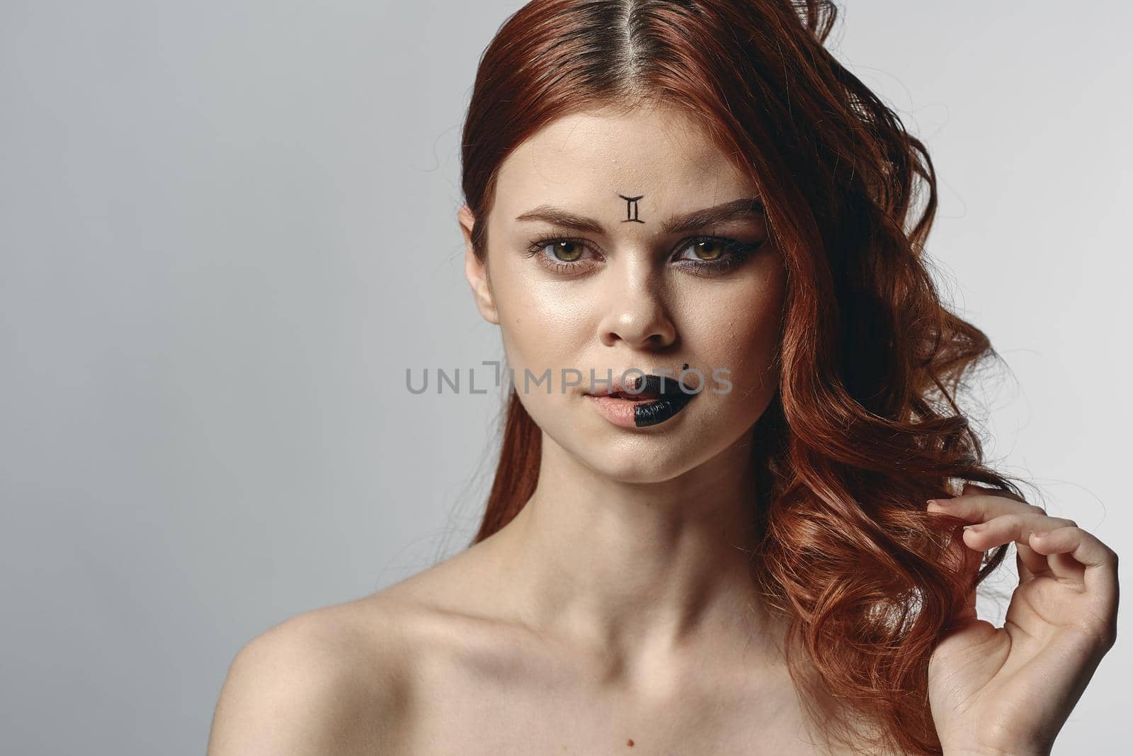 pretty woman with zodiac sign on her face red hair close-up. High quality photo