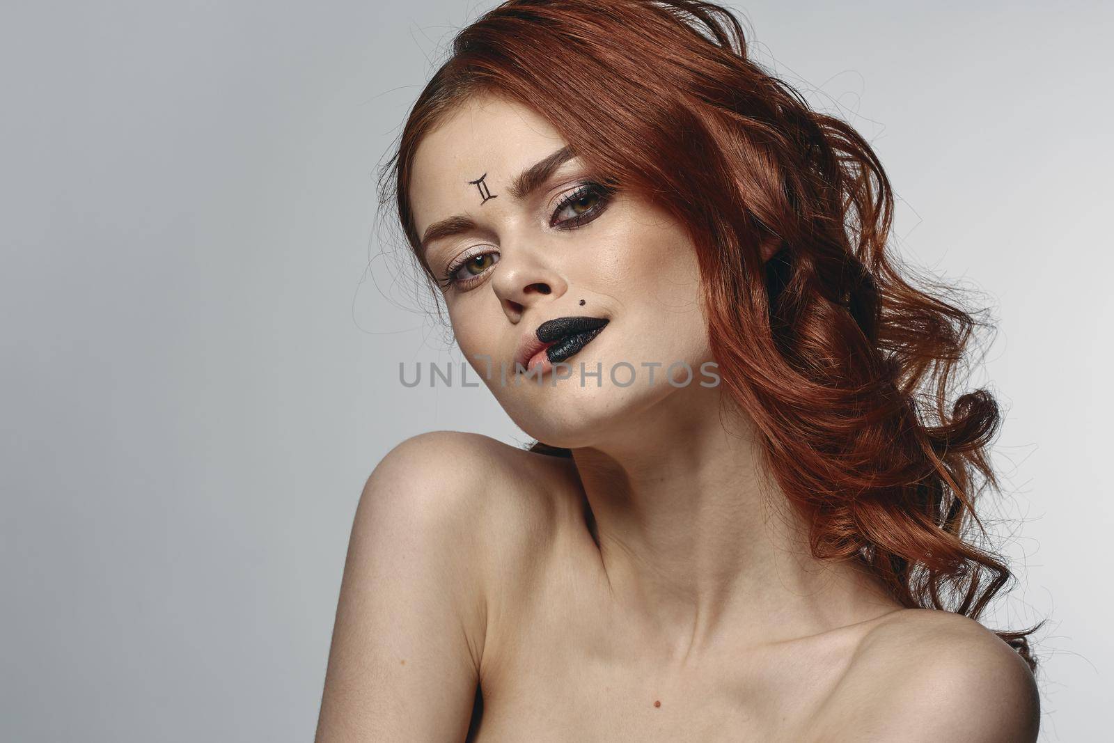red-haired woman naked shoulders zodiac sign on face gemini. High quality photo
