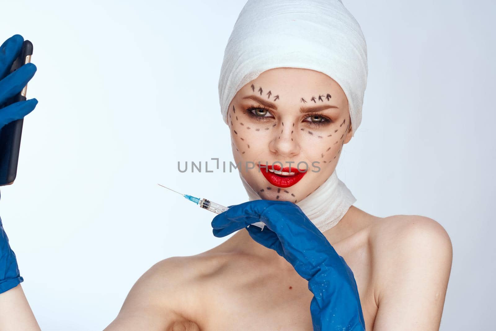 woman in blue gloves syringe in hands contour on the face lifting light background. High quality photo