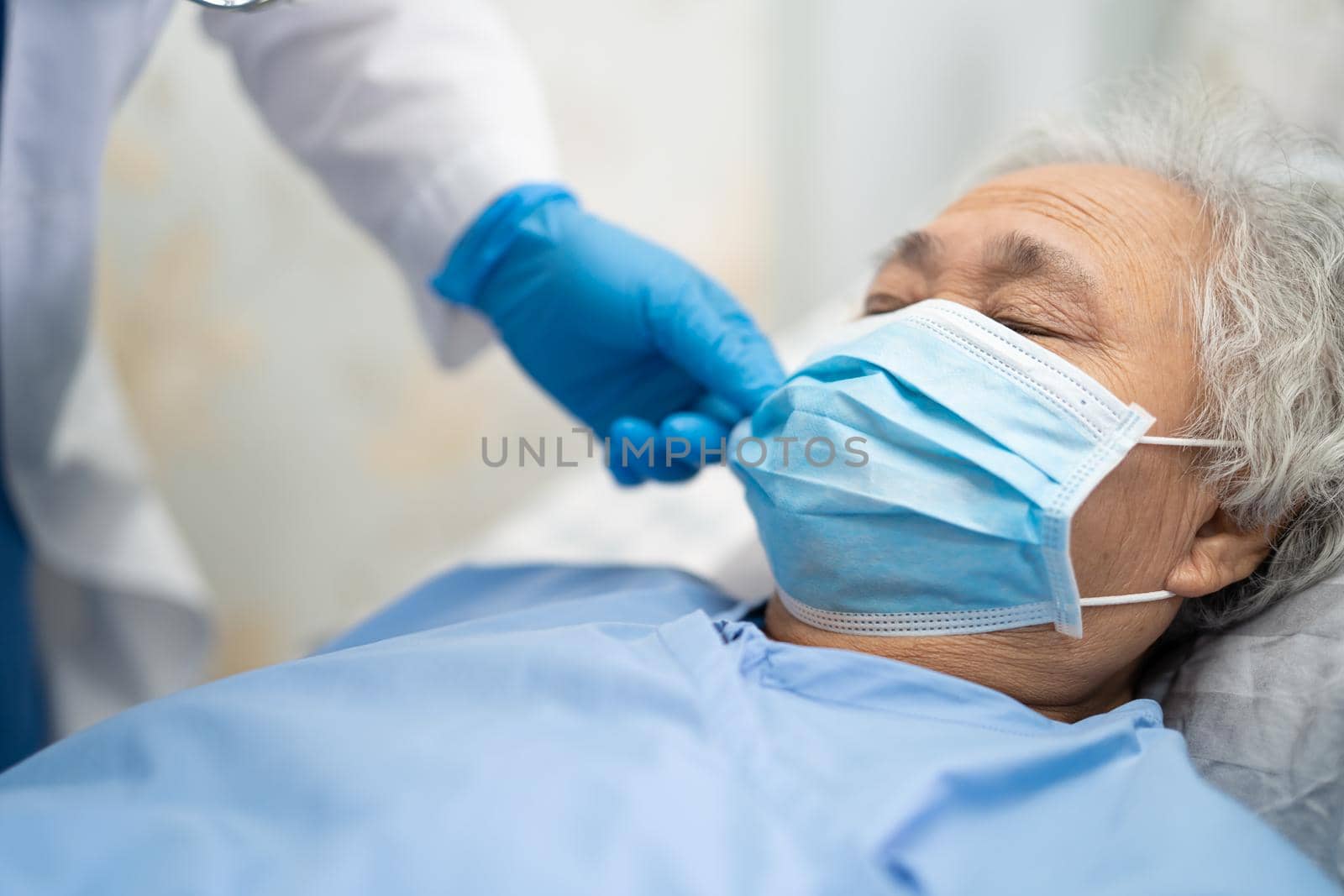 Asian doctor wearing PPE suit and glove new normal to check patient protect safety infection Covid-19 Coronavirus outbreak at quarantine nursing hospital ward.