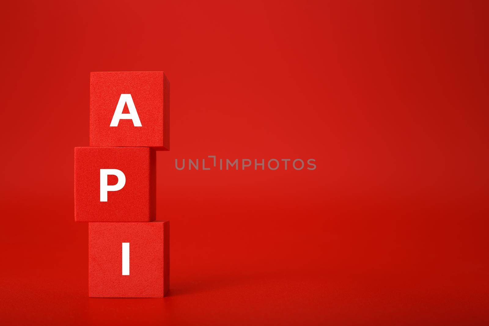 API concept in monochromatic red colors with copy space. API written on stack of red toy cubes. Application program interface